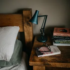 a stack of books sitting on top of a bed next to a lamp related to The Ultimate Guide to Choosing the Perfect Bed Size