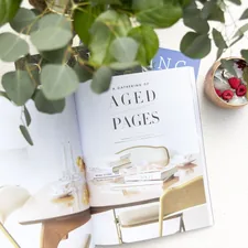 a table with a plant and a book on it related to Unveiling the Beauty of Pate Meadows Valances: A Guide to Elevating Your Home Decor