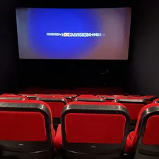 a theater with red seats and a projector screen related to Revolutionizing Comfort: The Rise of Movie Theatres with Beds