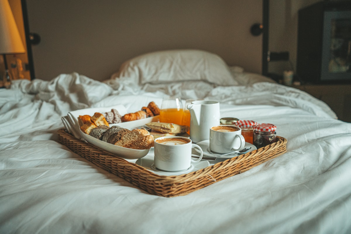 a tray of breakfast on a bed with white sheets related to Exploring the Charm of Bed and Breakfasts