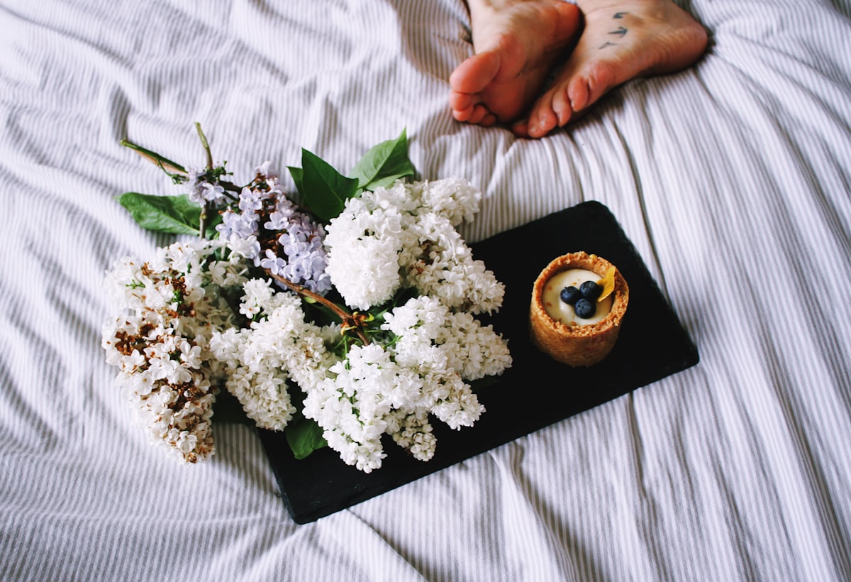a tray with flowers and a candle on a bed related to The Charm of Bed & Breakfast: A Cozy Getaway