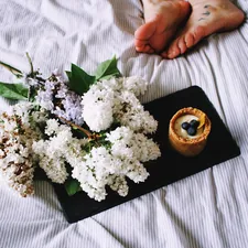 a tray with flowers and a candle on a bed related to The Charm of Bed & Breakfast: A Cozy Getaway