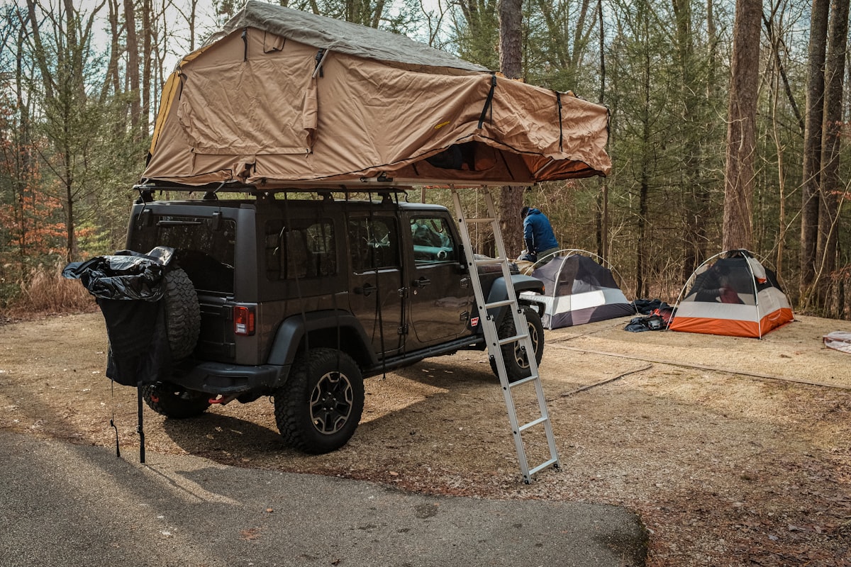 a van with a tent and a ladder in front of it related to The Ultimate Guide to Jeep Wrangler Bed Accessories and Upgrades