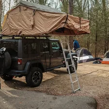 a van with a tent and a ladder in front of it related to The Ultimate Guide to Jeep Wrangler Bed Accessories and Upgrades