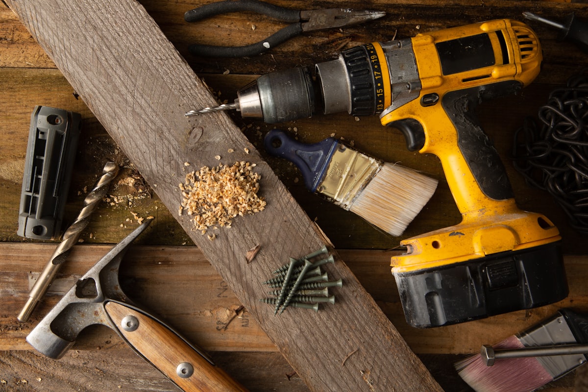 A variety of tools, including a hammer and cordless drill, sit on top of a table made of wood boards.  related to Step-by-Step Guide to Crafting a Wooden Bed Frame