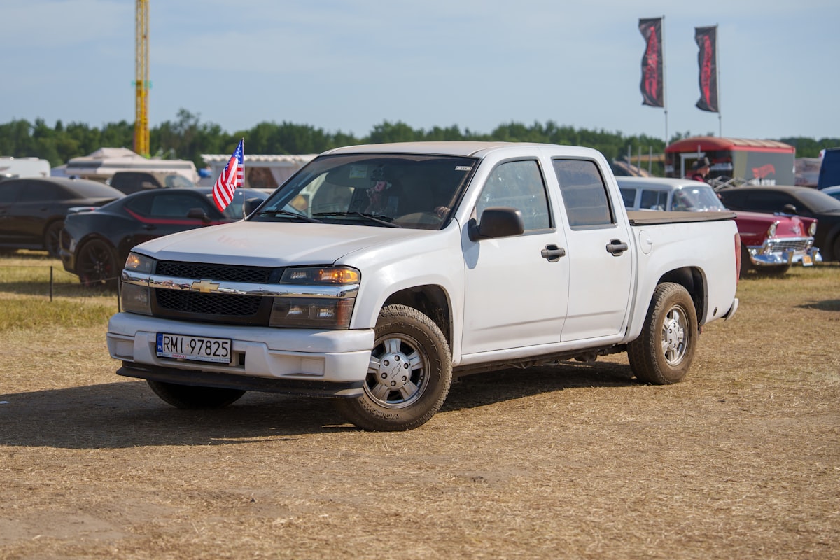 A white chevrolet pickup truck parked on a dirt field. related to Picking the Perfect Truck Bed Flag