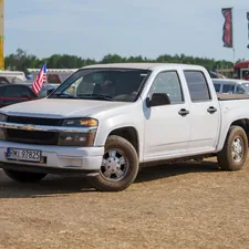 A white chevrolet pickup truck parked on a dirt field. related to Picking the Perfect Truck Bed Flag