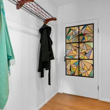 A white room with a coat rack and a painting on the wall related to The Art of Entryway Essentials