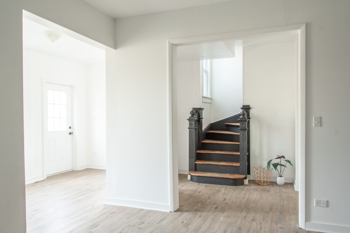 a white room with a staircase and a potted plant related to Enhancing Your Space: Entryway Rugs for Hardwood Floors