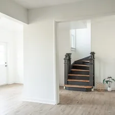 a white room with a staircase and a potted plant related to Enhancing Your Space: Entryway Rugs for Hardwood Floors