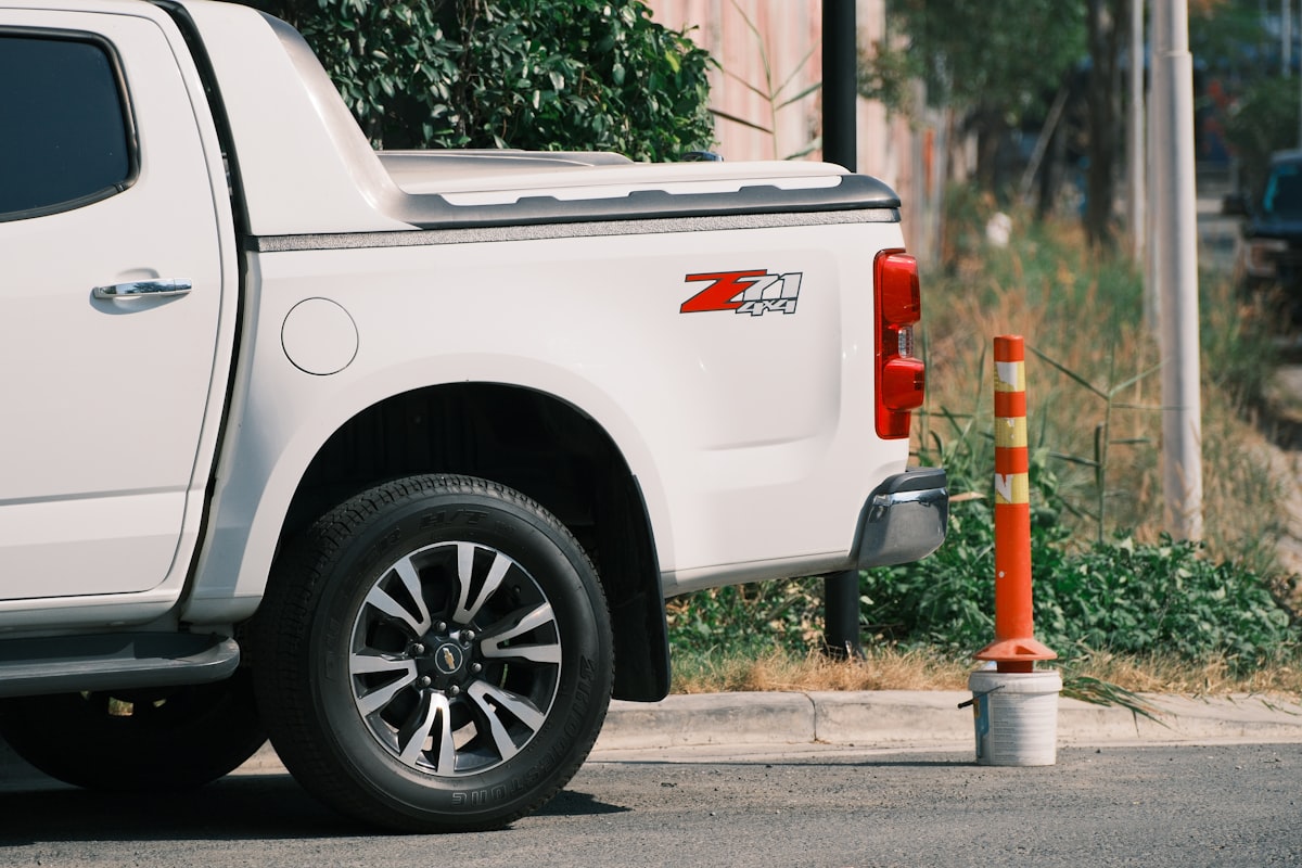 A white truck is parked next to a traffic cone. related to Roll with Security: The Ultimate Guide to Undercover Truck Bed Covers