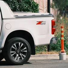 A white truck is parked next to a traffic cone. related to Roll with Security: The Ultimate Guide to Undercover Truck Bed Covers