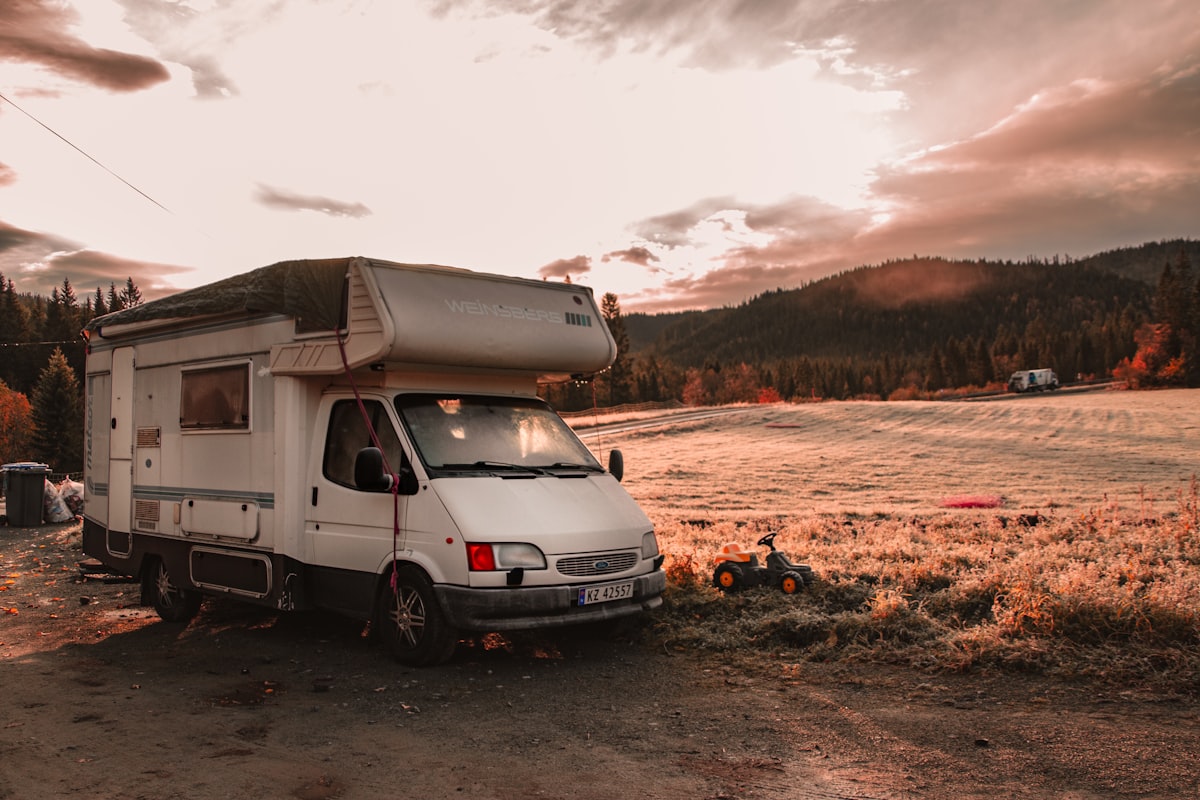 a white van parked on a dirt road with a hill and trees in the background related to Exploring the Best Motorhomes with Bunk Beds for Family Adventures