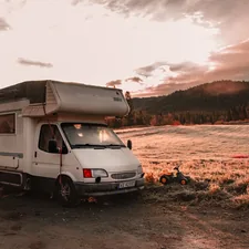 a white van parked on a dirt road with a hill and trees in the background related to Exploring the Best Motorhomes with Bunk Beds for Family Adventures