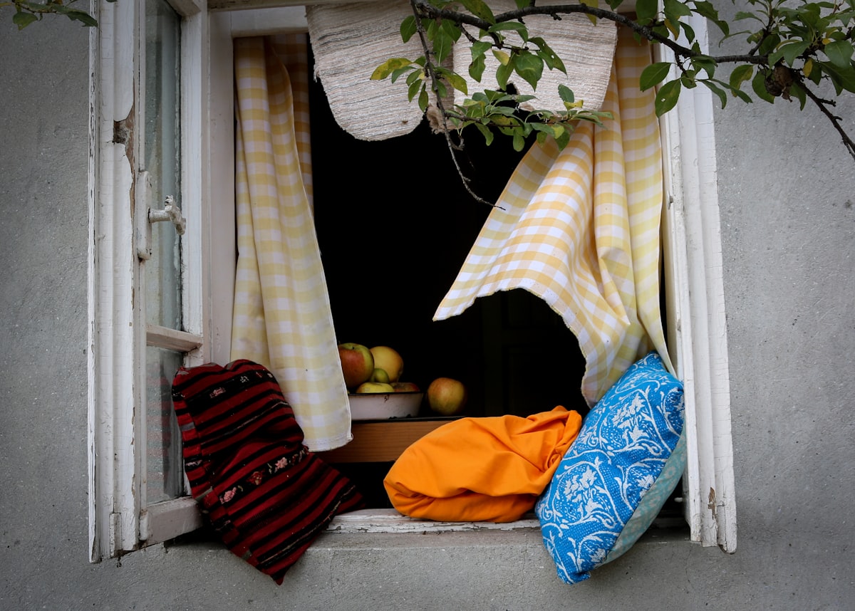 a window sill with a bunch of cloths hanging out of it related to Scarf Valance: Creative Window Treatment Ideas