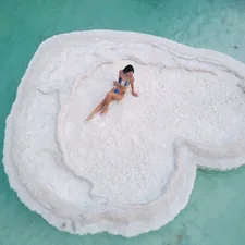 a woman is sitting on a rock in the water related to A Heart Shaped Bed: The Ultimate Symbol of Romance