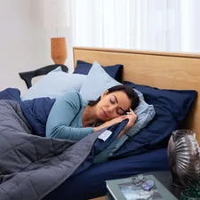 a woman laying in bed talking on a cell phone related to Soft and Cozy: The Best Cotton Coverlets for Beds