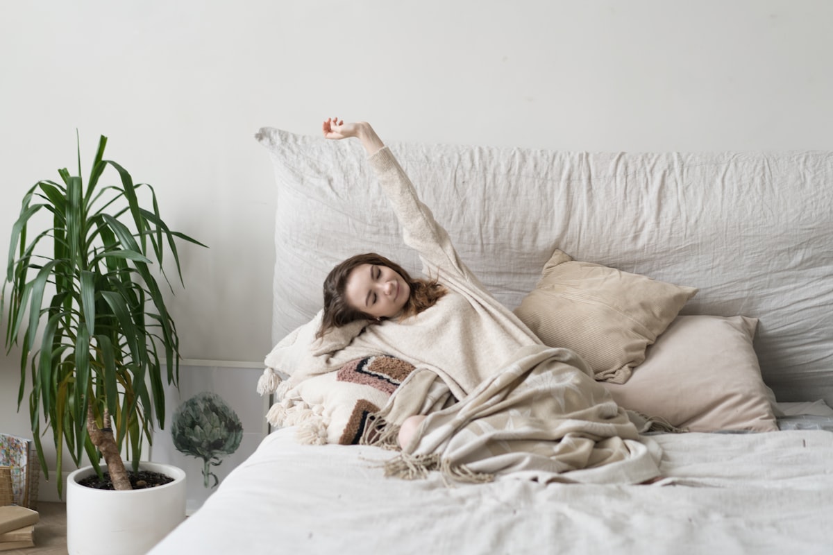 a woman laying on a bed with a blanket related to Elevate Your Sleep Sanctuary: The Underrated Power of Elasticated Bed Valances