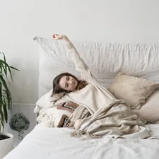a woman laying on a bed with a blanket related to Elevate Your Sleep Sanctuary: The Underrated Power of Elasticated Bed Valances