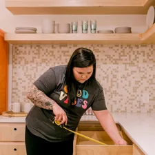A woman measures a kitchen drawer with a tape measure. related to Maximize Your Space with a Full-Size Storage Bed