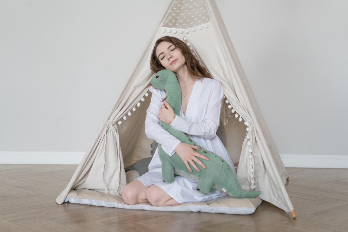a woman sitting in a teepee holding a stuffed animal related to Bring Prehistoric Fun to Your Bedroom with Dinosaur Bedding Sets