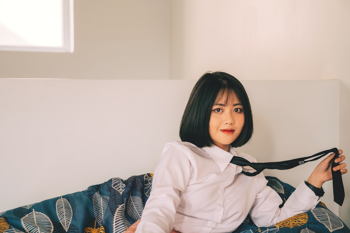 a woman sitting on a bed holding a tie related to Anime Dreams: Slumbering in Style with Themed Bedding