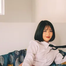 a woman sitting on a bed holding a tie related to Anime Dreams: Slumbering in Style with Themed Bedding