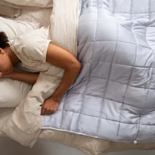 a woman sleeping in a bed with a white comforter related to Lightweight Quilts and Coverlets: The Ultimate Guide
