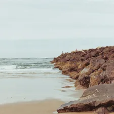 a woman standing on a rocky beach next to the ocean related to Indulge in Coastal Serenity at Cambria's Finest Bed and Breakfasts