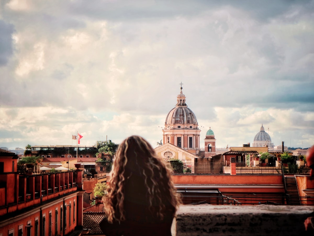 a woman standing on top of a roof next to a tall building related to Discover the Charm of Rome Bed and Breakfasts