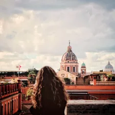 a woman standing on top of a roof next to a tall building related to Discover the Charm of Rome Bed and Breakfasts