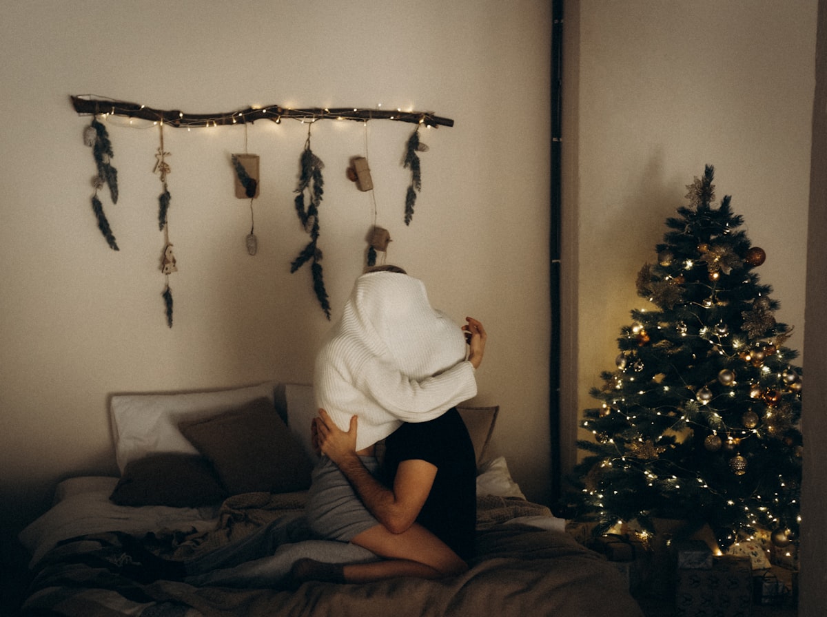a woman wrapped in a blanket sitting on a bed related to Cozy Comfort: Embrace the Spirit of the Dallas Cowboys with Official Bedding