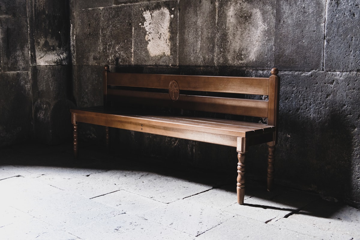 a wooden bench sitting in front of a stone wall related to Revamping Your Home with Corner Entryway Benches