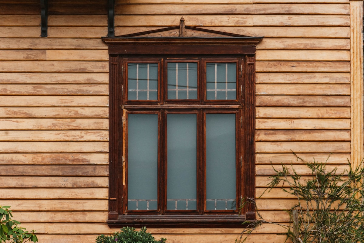 a wooden building with a window and a plant in front of it related to Elevate Your Windows with Beaded Window Valances
