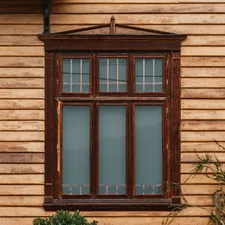 a wooden building with a window and a plant in front of it related to Elevate Your Windows with Beaded Window Valances