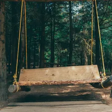 a wooden swing in the middle of a forest related to Building Your Dream Porch: A DIY Guide