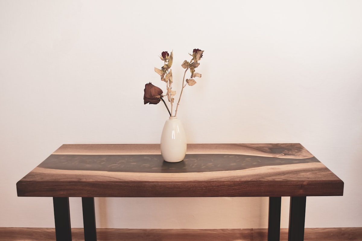 a wooden table with a vase of flowers on top of it related to Stunning Unique Entryway Tables to Elevate Your Home's Style