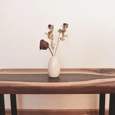 a wooden table with a vase of flowers on top of it related to Stunning Unique Entryway Tables to Elevate Your Home's Style