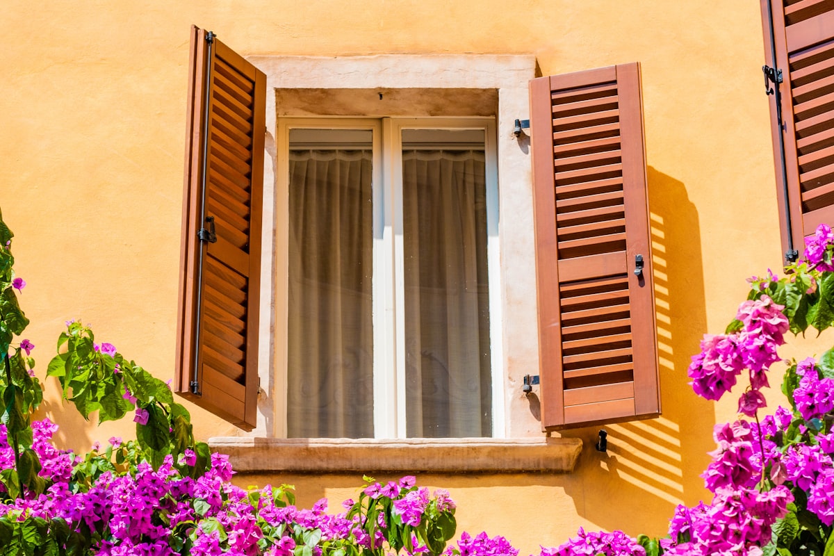 a yellow building with red shutters and purple flowers related to JCP Window Valances: Enhance Your Home's Beauty