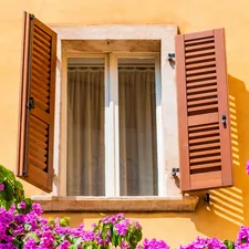 a yellow building with red shutters and purple flowers related to JCP Window Valances: Enhance Your Home's Beauty