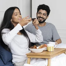 A young couple having breakfast in an adjustable bed related to Elevate Your Sleep: The Unexpected Benefits of a Bed Wedge Pillow
