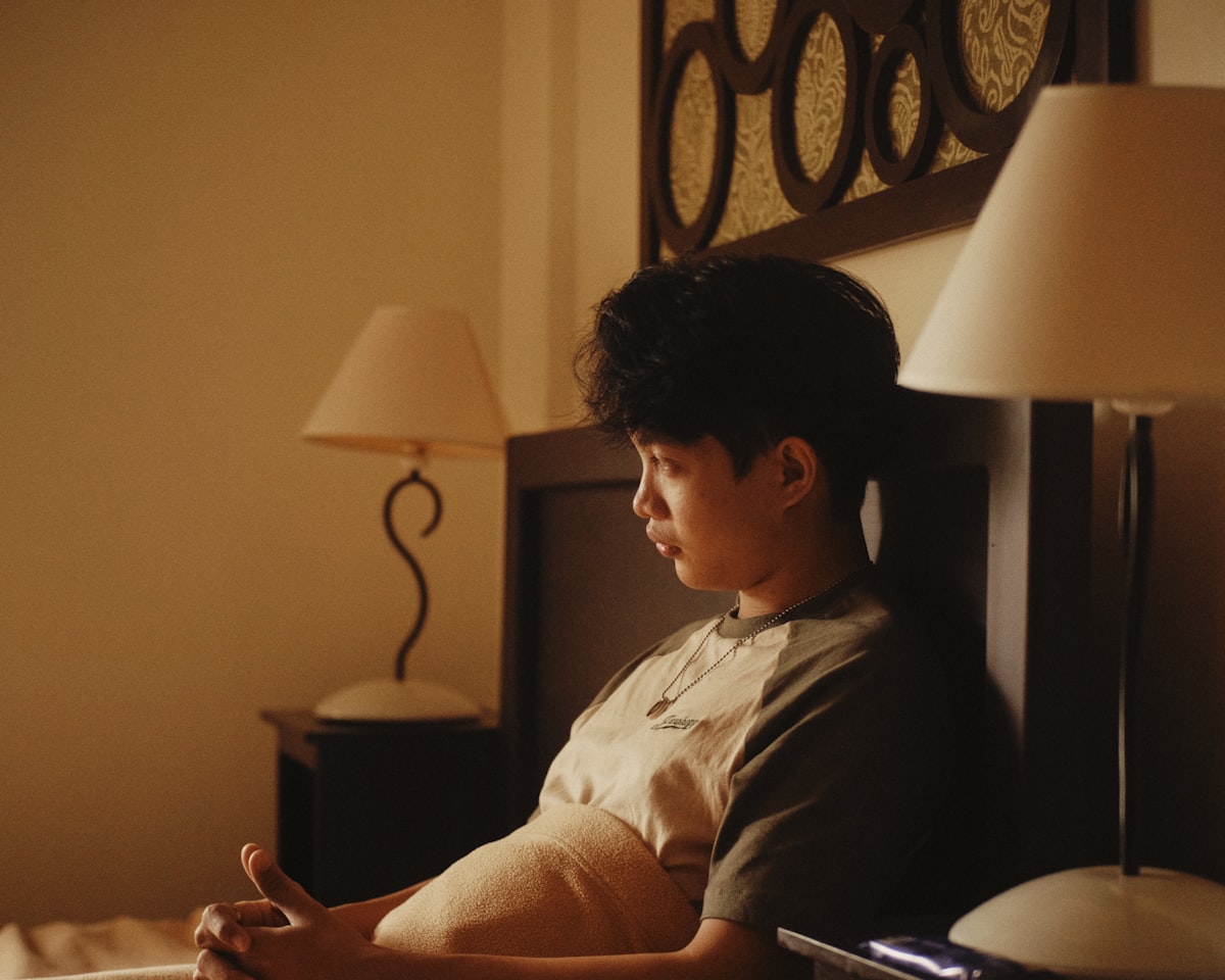 a young man sitting on a bed in a hotel room related to The Ultimate Guide to Choosing a Baby Sleeper for In-Bed Comfort