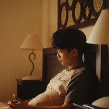 a young man sitting on a bed in a hotel room related to The Ultimate Guide to Choosing a Baby Sleeper for In-Bed Comfort