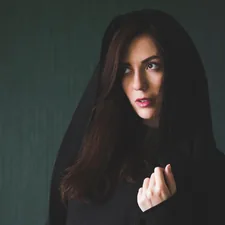 a young woman in a robe with a hood on her head looks to the left on a dark green background.
say "Thanks" via PayPal :) related to The Mysterious Allure of the Bed of Nails: Uncovering its Secrets