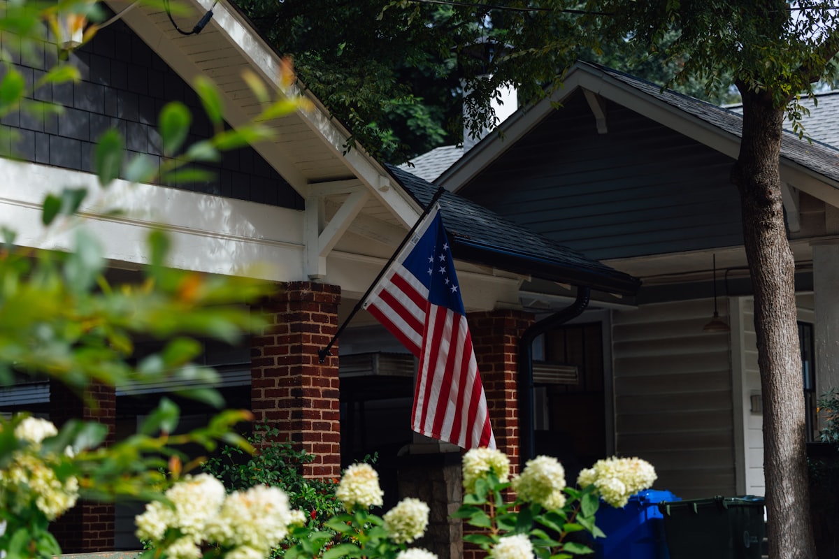 American flag hanging on a house porch with white flowers. related to Charming Escapes: Your Guide to Atlanta's Best Bed and Breakfasts