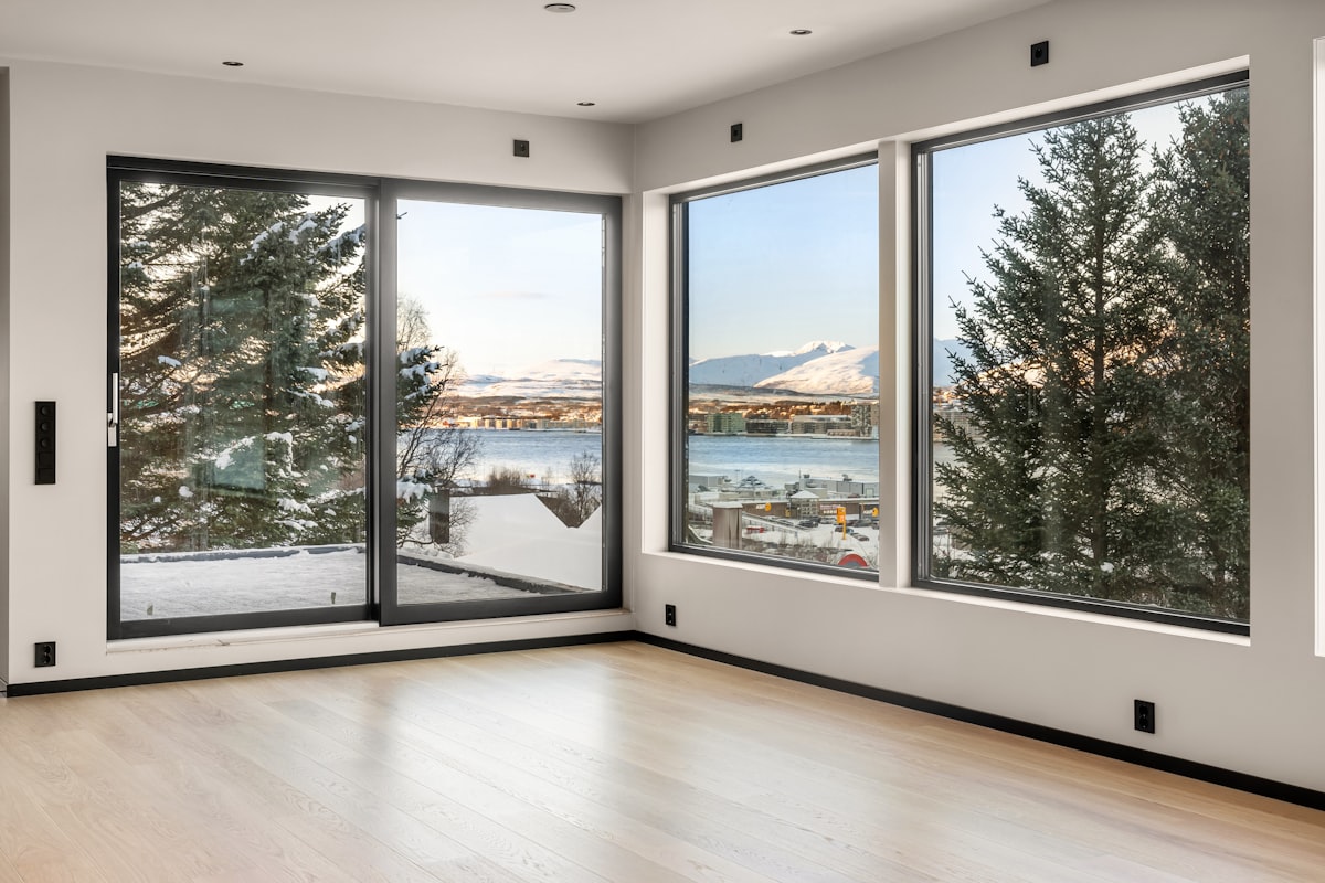 An empty room with large windows overlooking a lake related to Elevate Your Windows with Custom Valances