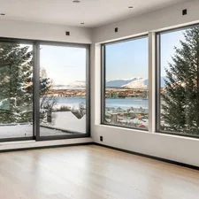 An empty room with large windows overlooking a lake related to Elevate Your Windows with Custom Wood Cornice Valance