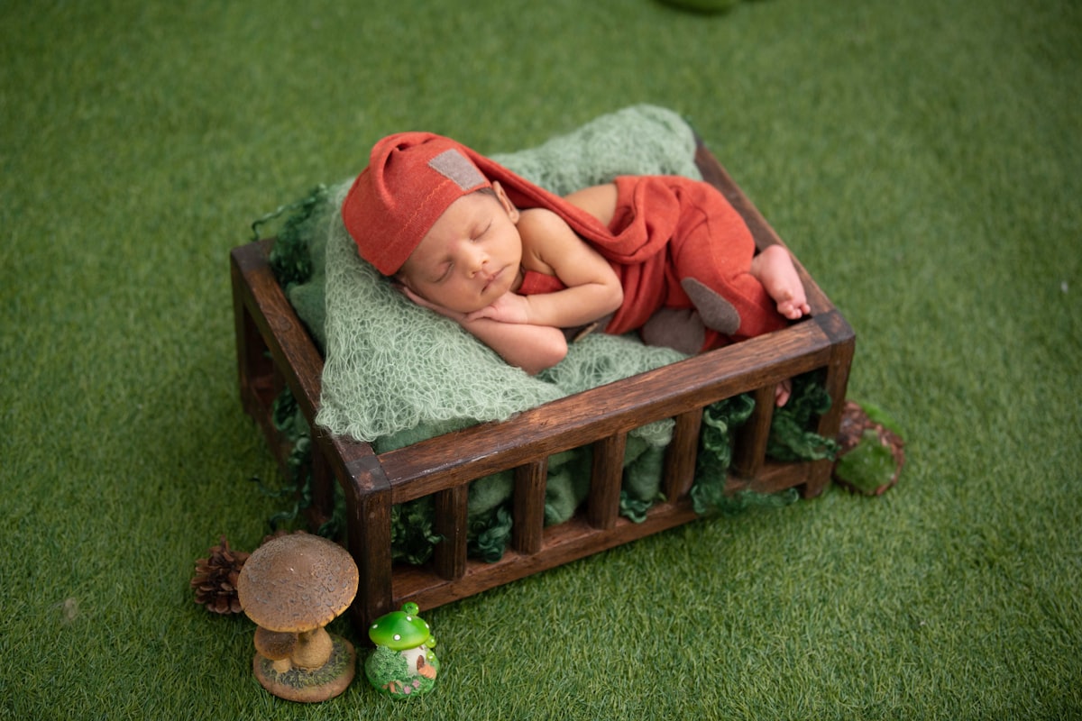 baby in red and white stripe onesie lying on brown wooden bed related to Snuggle and Snort: Creating a Cozy Nest for Your New Arrival
