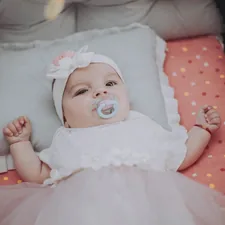 baby in white dress lying on bed related to Cozying Up Your Baby Girl: Trends and Essentials for Baby Girl Crib Bedding