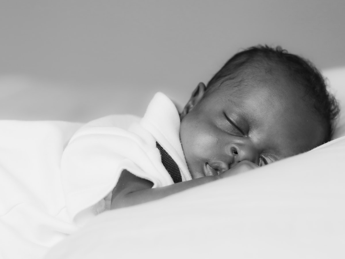 baby in white shirt lying on bed related to Creating a Timeless Nursery: Essentials for Black and White Baby Bedding